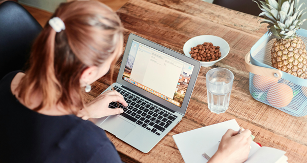 A woman is sitting at a desk, working on her laptop.